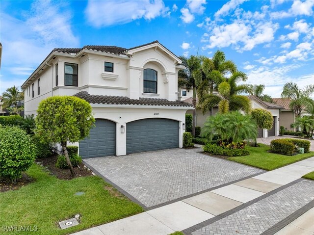 4083 Aspen Chase Dr, Naples, FL 34119 - mediterranean / spanish home featuring stucco siding, a tiled roof, an attached garage, decorative driveway, and a front lawn