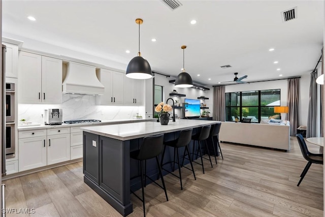 4083 Aspen Chase Dr, Naples, FL 34119 - kitchen featuring premium range hood, open floor plan, light countertops, light wood-style flooring, and white cabinetry