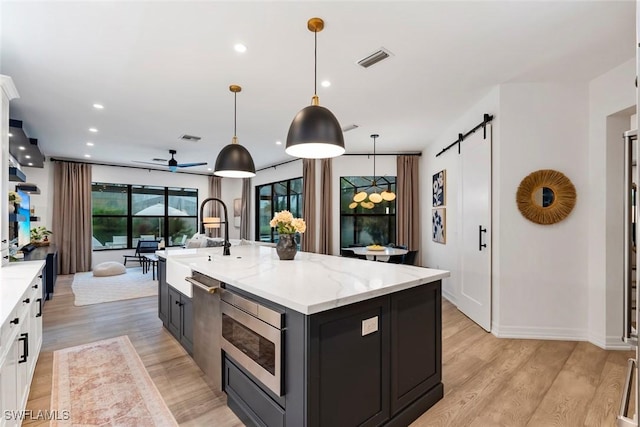 4083 Aspen Chase Dr, Naples, FL 34119 - kitchen featuring stainless steel microwave, a barn door, light wood-type flooring, recessed lighting, and a ceiling fan