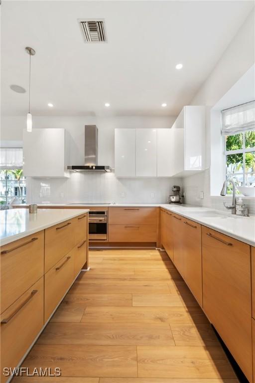 687 9th Ave S, Naples, FL 34102 - kitchen with wall chimney range hood, modern cabinets, light countertops, pendant lighting, and recessed lighting