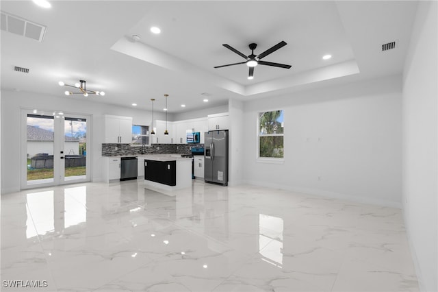 2813 38th St SW, Lehigh Acres, FL 33976 - kitchen with stainless steel appliances, open floor plan, a tray ceiling, a kitchen island, and healthy amount of natural light