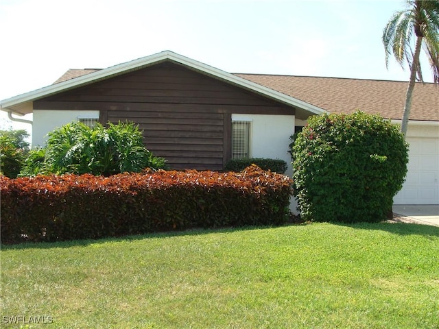 4802 Lakewood Blvd Unit B13, Naples, FL 34112 - view of property exterior with a lawn, stucco siding, a garage, and a shingled roof