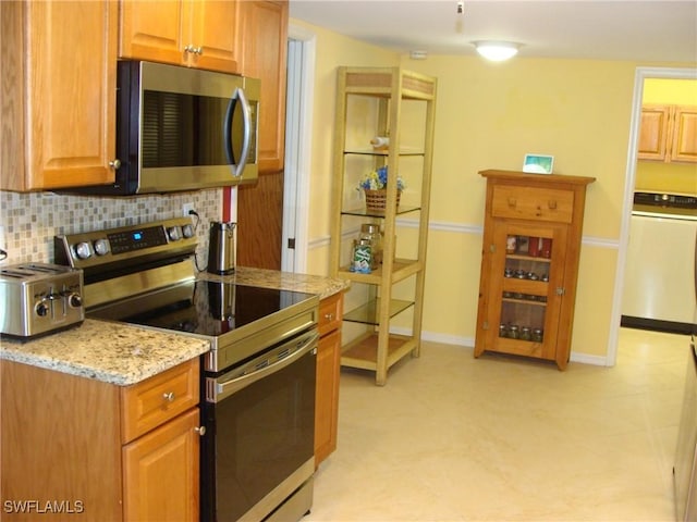 4802 Lakewood Blvd Unit B13, Naples, FL 34112 - kitchen with appliances with stainless steel finishes, washer / dryer, backsplash, light stone countertops, and baseboards