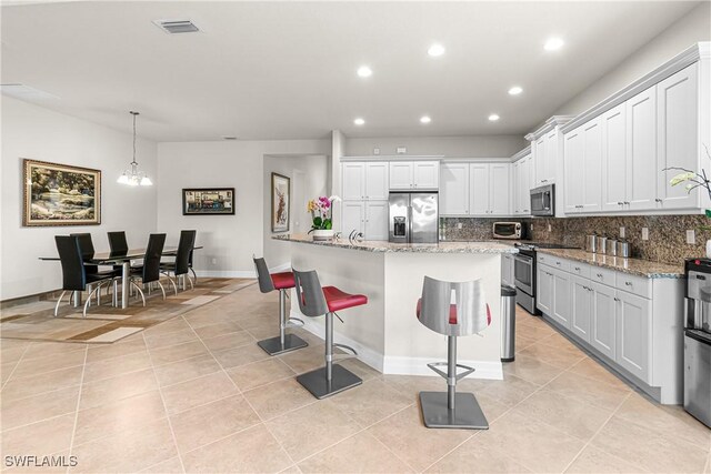 11704 Stonecreek Cir, Fort Myers, FL 33913 - kitchen with stainless steel appliances, light tile patterned flooring, recessed lighting, decorative backsplash, and a breakfast bar area