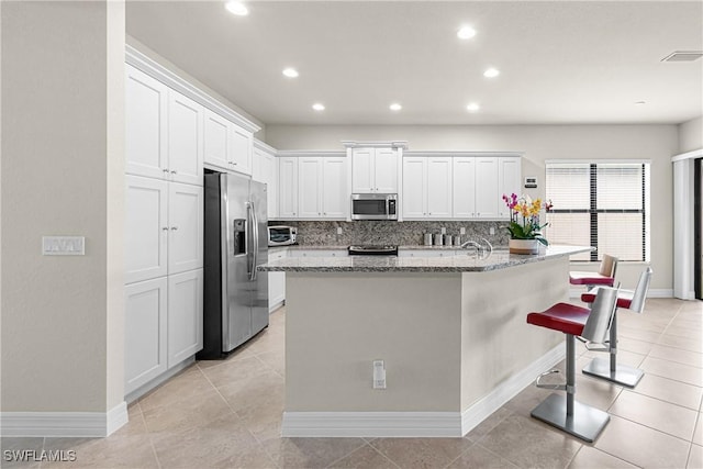 11704 Stonecreek Cir, Fort Myers, FL 33913 - kitchen featuring appliances with stainless steel finishes, decorative backsplash, white cabinetry, light stone countertops, and baseboards