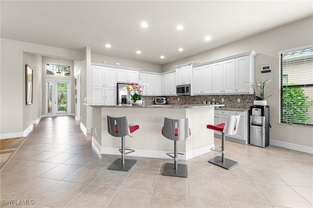 11704 Stonecreek Cir, Fort Myers, FL 33913 - kitchen featuring appliances with stainless steel finishes, light tile patterned floors, tasteful backsplash, a breakfast bar area, and recessed lighting