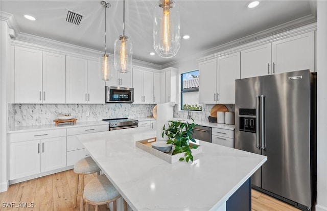 7049 Chapel Creek Ln, North Fort Myers, FL 33917 - kitchen with appliances with stainless steel finishes, white cabinetry, light countertops, a kitchen island, and pendant lighting