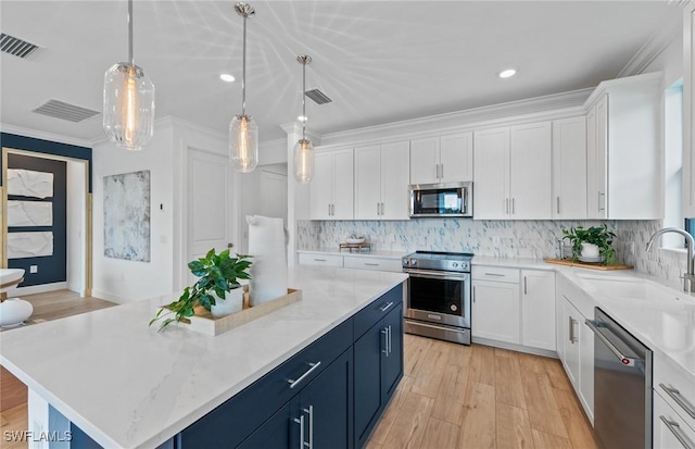 7049 Chapel Creek Ln, North Fort Myers, FL 33917 - kitchen featuring appliances with stainless steel finishes, a sink, blue cabinetry, a center island, and crown molding