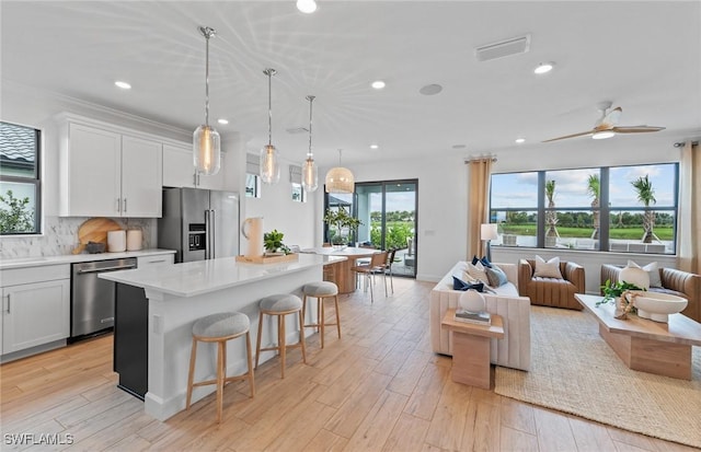 7049 Chapel Creek Ln, North Fort Myers, FL 33917 - kitchen with stainless steel appliances, open floor plan, a kitchen island, light countertops, and a breakfast bar