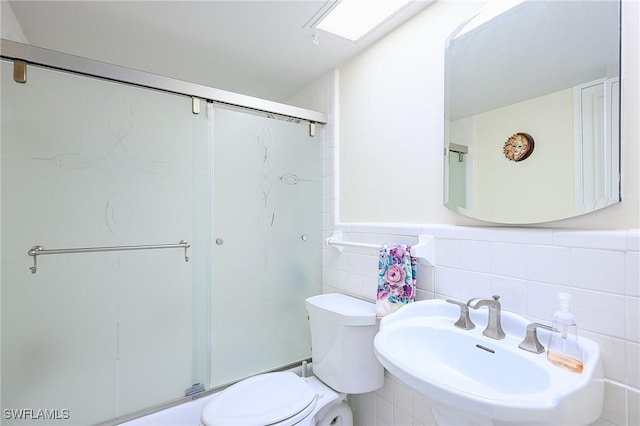 1100 8th Ave S Unit 309C, Naples, FL 34102 - bathroom featuring a sink, toilet, a shower stall, tile walls, and a wainscoted wall