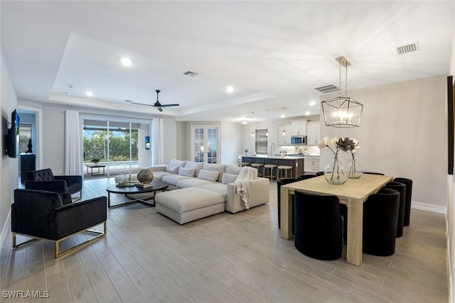 28086 Captiva Shell Loop, Bonita Springs, FL 34135 - living room with a raised ceiling, light wood finished floors, baseboards, a ceiling fan, and a chandelier