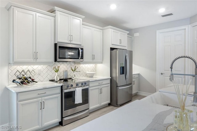 28086 Captiva Shell Loop, Bonita Springs, FL 34135 - kitchen with appliances with stainless steel finishes, decorative backsplash, a sink, light stone countertops, and white cabinetry