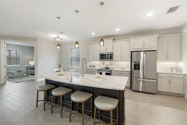 28086 Captiva Shell Loop, Bonita Springs, FL 34135 - kitchen featuring stainless steel appliances, light wood-style floors, decorative backsplash, a center island with sink, and recessed lighting