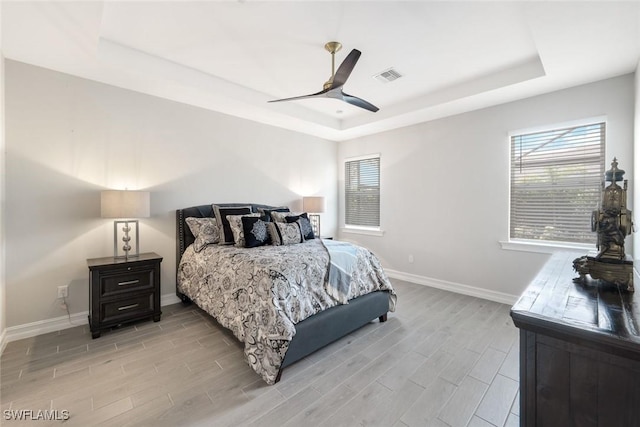 28086 Captiva Shell Loop, Bonita Springs, FL 34135 - bedroom featuring a tray ceiling, baseboards, light wood-type flooring, and multiple windows