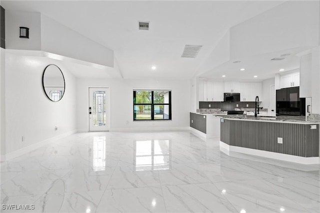 3613 39th St SW, Lehigh Acres, FL 33976 - kitchen featuring black microwave, light marble finish floors, open floor plan, lofted ceiling, and white cabinetry