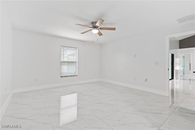 3613 39th St SW, Lehigh Acres, FL 33976 - empty room featuring light marble finish flooring, a ceiling fan, and baseboards