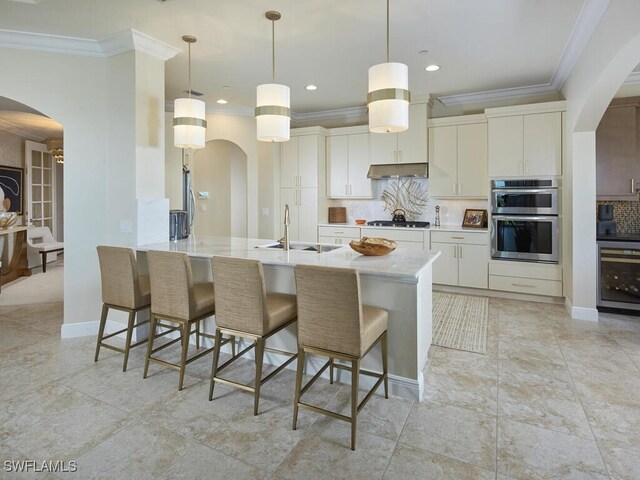 4701 Via Del Corso Ln Unit 401, Bonita Springs, FL 34134 - kitchen with arched walkways, stainless steel double oven, ornamental molding, gas cooktop, and under cabinet range hood