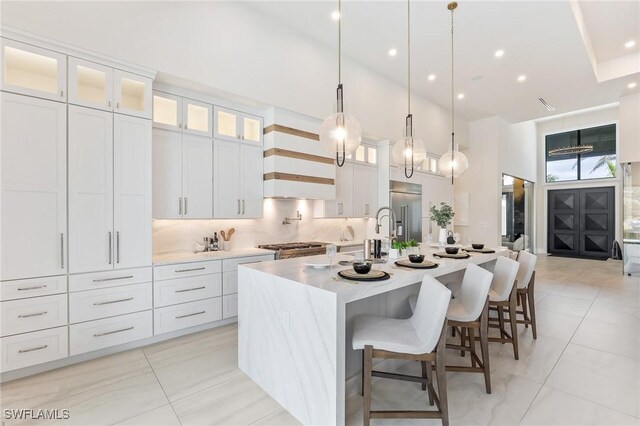 160 SW 52nd Ter, Cape Coral, FL 33914 - kitchen with high end fridge, a spacious island, a towering ceiling, light countertops, and white cabinetry