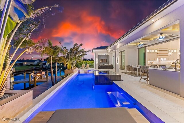 160 SW 52nd Ter, Cape Coral, FL 33914 - pool at dusk with an outdoor bar, an outdoor kitchen, an outdoor pool, a patio, and ceiling fan