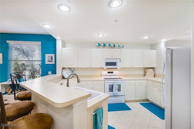 4011 Palm Tree Blvd Unit 208, Cape Coral, FL 33904 - kitchen with white appliances, a kitchen breakfast bar, white cabinetry, light tile patterned floors, and a peninsula
