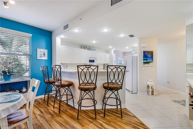 4011 Palm Tree Blvd Unit 208, Cape Coral, FL 33904 - kitchen with white appliances, a kitchen bar, white cabinets, baseboards, and recessed lighting
