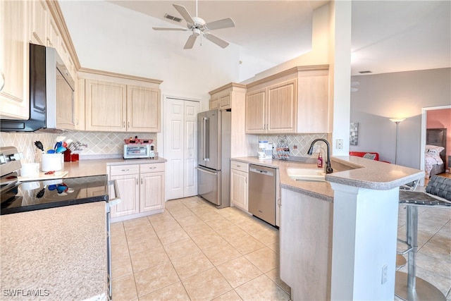 14561 Glen Cove Dr Unit 904, Fort Myers, FL 33919 - kitchen with stainless steel appliances, a kitchen bar, a ceiling fan, a peninsula, and decorative backsplash
