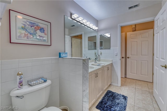 14561 Glen Cove Dr Unit 904, Fort Myers, FL 33919 - bathroom featuring tile walls, tile patterned flooring, toilet, double vanity, and a wainscoted wall