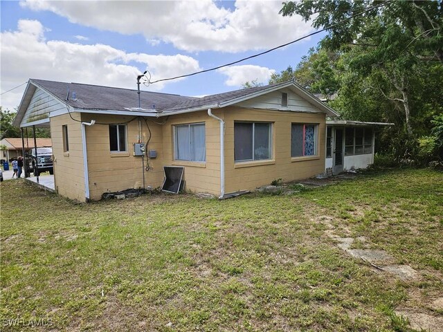 1112 Evanston St, Sebring, FL 33870 - back of house with a yard, a sunroom, concrete block siding, and roof with shingles