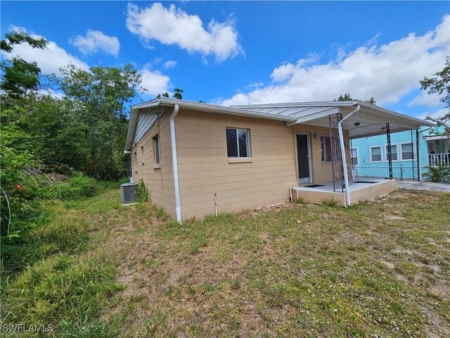 1112 Evanston St, Sebring, FL 33870 - back of house featuring a patio area, cooling unit, a standing seam roof, and a lawn