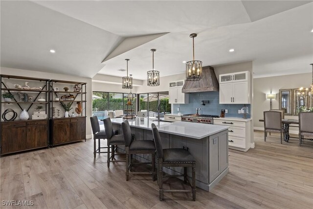 1020 SW 56th St, Cape Coral, FL 33914 - kitchen with a chandelier, white cabinets, light wood-style flooring, light countertops, and custom exhaust hood