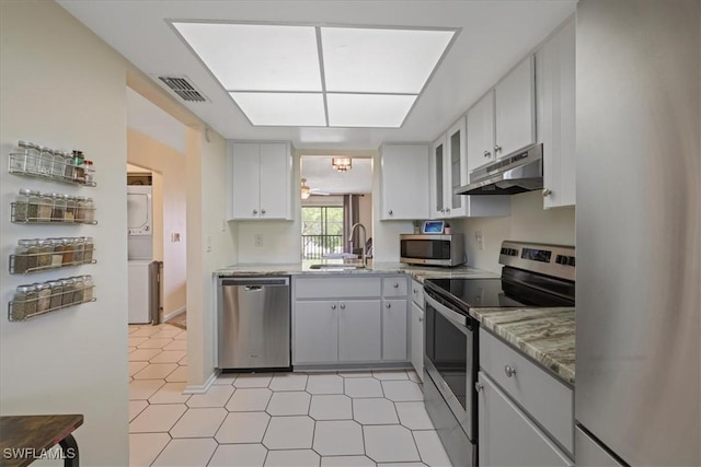 503 Cape Coral Pkwy W Unit 201, Cape Coral, FL 33914 - kitchen with appliances with stainless steel finishes, estacked washer and dryer, under cabinet range hood, a sink, and light stone counters
