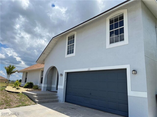 23 NW 22nd Ave, Cape Coral, FL 33993 - view of front facade featuring stucco siding, an attached garage, and driveway