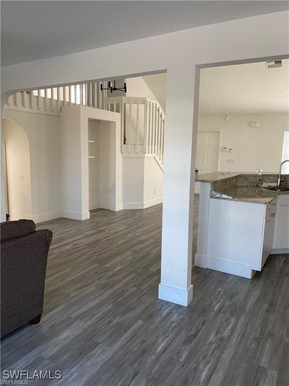 23 NW 22nd Ave, Cape Coral, FL 33993 - kitchen with arched walkways, baseboards, dark wood finished floors, open floor plan, and dark stone counters