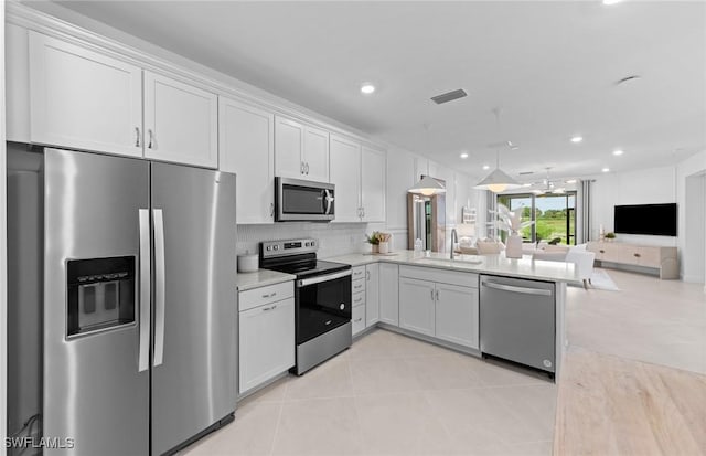 6470 Memorial Ln, Ave Maria, FL 34142 - kitchen with stainless steel appliances, a sink, open floor plan, light tile patterned flooring, and white cabinetry