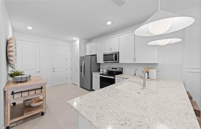 6470 Memorial Ln, Ave Maria, FL 34142 - kitchen with appliances with stainless steel finishes, a sink, light stone counters, white cabinetry, and a peninsula
