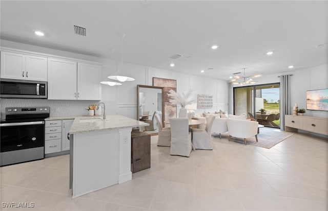 6470 Memorial Ln, Ave Maria, FL 34142 - kitchen with stainless steel appliances, a chandelier, open floor plan, light stone counters, and white cabinetry