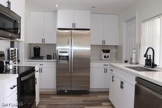 5750 N Andrews Ave, Oakland Park, FL 33309 - kitchen with appliances with stainless steel finishes, a sink, light countertops, white cabinetry, and wood finished floors