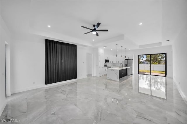 1925 NW 30th Ter, Cape Coral, FL 33993 - unfurnished living room with a tray ceiling, recessed lighting, a ceiling fan, light marble finish flooring, and baseboards