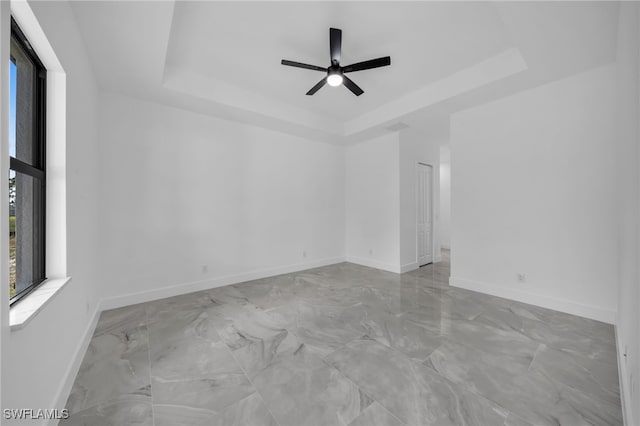 1925 NW 30th Ter, Cape Coral, FL 33993 - spare room with a tray ceiling, marble finish flooring, ceiling fan, and baseboards