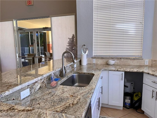 6401 Aragon Way Unit 102, Fort Myers, FL 33966 - kitchen featuring french doors, a sink, white cabinets, light tile patterned floors, and light stone countertops