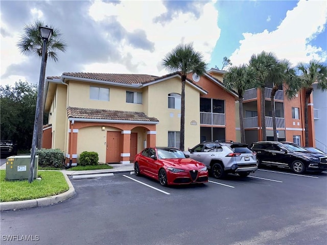 6401 Aragon Way Unit 102, Fort Myers, FL 33966 - view of front facade featuring uncovered parking, a tile roof, and stucco siding