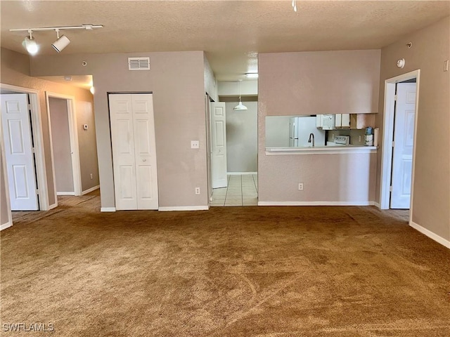 6401 Aragon Way Unit 102, Fort Myers, FL 33966 - unfurnished living room with carpet, a textured ceiling, track lighting, and baseboards