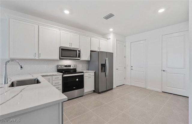 6459 Memorial Ln, Ave Maria, FL 34142 - kitchen featuring stainless steel appliances, a sink, white cabinetry, backsplash, and light tile patterned floors