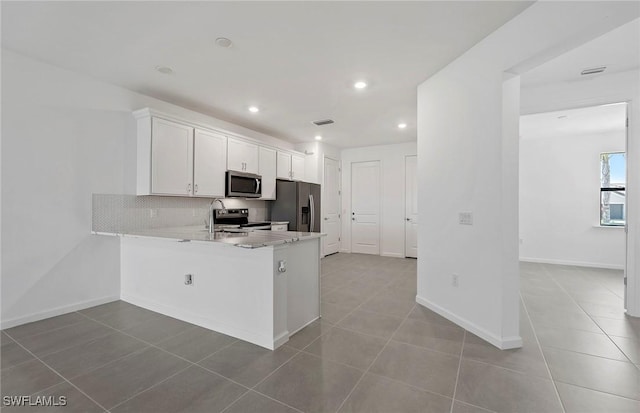 6459 Memorial Ln, Ave Maria, FL 34142 - kitchen with appliances with stainless steel finishes, tile patterned floors, decorative backsplash, white cabinetry, and recessed lighting