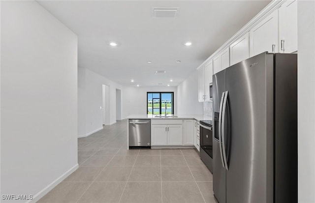 6459 Memorial Ln, Ave Maria, FL 34142 - kitchen with appliances with stainless steel finishes, a peninsula, light tile patterned flooring, white cabinetry, and recessed lighting