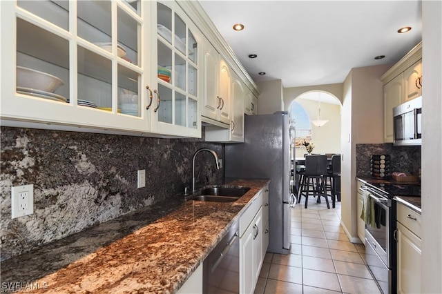 17260 Eagle Trce Unit 10, Fort Myers, FL 33908 - kitchen with stainless steel appliances, a sink, light tile patterned flooring, glass insert cabinets, and tasteful backsplash