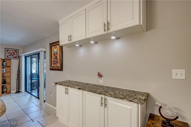 7116 Blanquilla Ct Unit 220, Fort Myers, FL 33908 - kitchen featuring white cabinetry, dark stone countertops, light tile patterned flooring, and baseboards