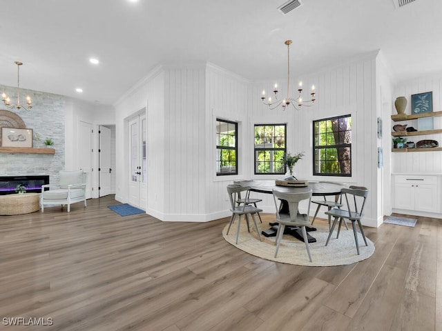 16970 Laurelin Ct, North Fort Myers, FL 33917 - dining space featuring a chandelier, crown molding, wood finished floors, a stone fireplace, and baseboards
