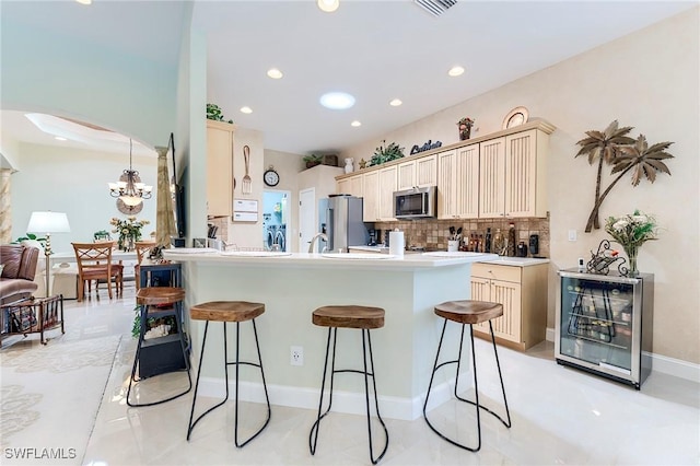 3181 Bramble Cove Ct, Fort Myers, FL 33905 - kitchen featuring appliances with stainless steel finishes, a kitchen bar, cream cabinets, backsplash, and recessed lighting