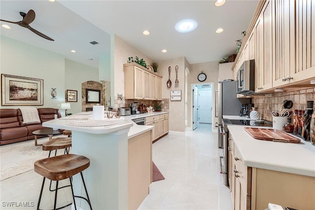 3181 Bramble Cove Ct, Fort Myers, FL 33905 - kitchen featuring appliances with stainless steel finishes, open floor plan, a breakfast bar, tasteful backsplash, and a ceiling fan
